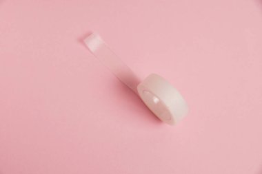 Flatlay, medical transparent plaster for applying bandages on a pink background.