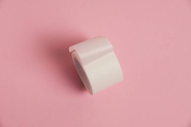 White medical patch on a paper base, for applying bandages, on a pink background.