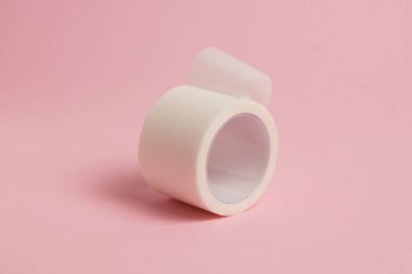 White medical patch on a paper base, for applying bandages, on a pink background.