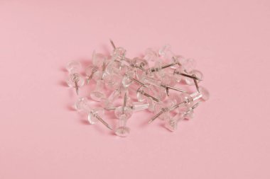 Transparent push pins on paper pink background with copy space.