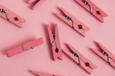 Flatlay, pink, wooden clothespins on paper background.