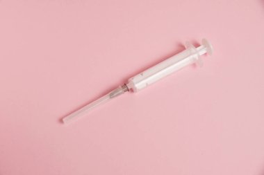Flatlay, syringe on paper pink background with copy space.