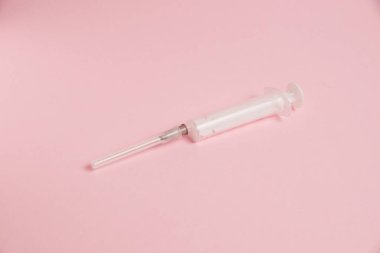 Flatlay, syringe on paper pink background with copy space.