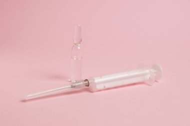 Syringe and ampoule with painkiller on pink paper background.