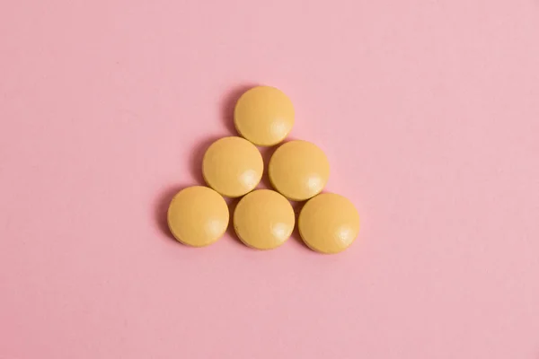 Yellow vitamins in pills on a pink paper background. Concept of immunity support in spring