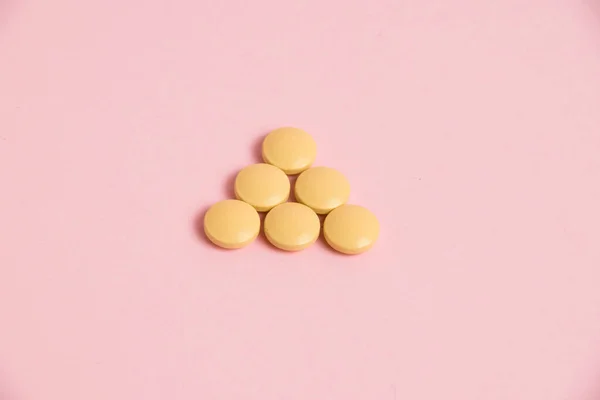 Yellow vitamins in pills on a pink paper background. Concept of immunity support in spring