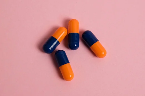 Multicolored pills on pink paper background with copy space, flatlay. Concept of treatment of covid 19 and colds