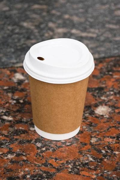 Disposable paper cup with cocoa on a marble tile.