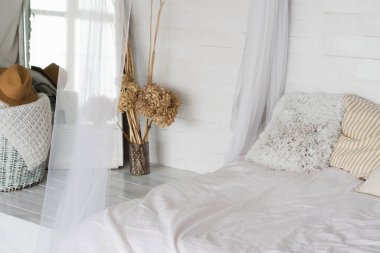 Bright room, bed with pillows and white bedspread, mirror. Concept of space organization in a small bedroom.