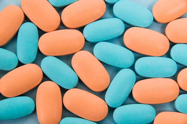 Pattern, blue and pink vitamins in pills for men and women on blue paper flatlay background. The concept of differences in the needs of the female and male gender.