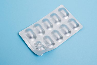 Opened blister pack with pills on a blue paper background.