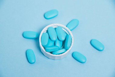 Blue pills on blue background with flat lay copy space. Vitamins for men