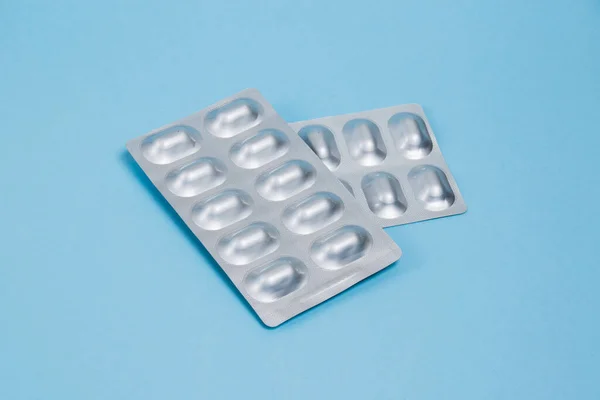 Pills in silver blisters on a blue paper background. Probiotics in a package