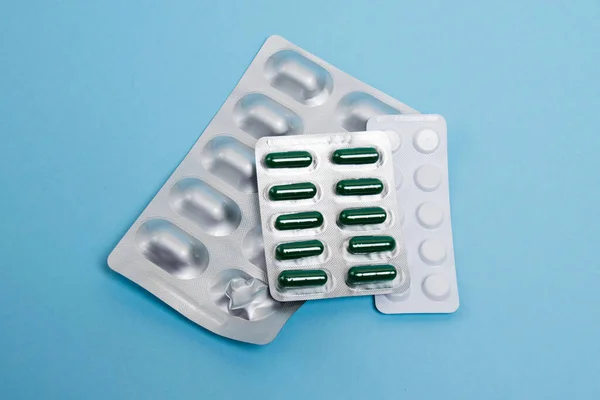 Several blisters with pills on a blue paper background.