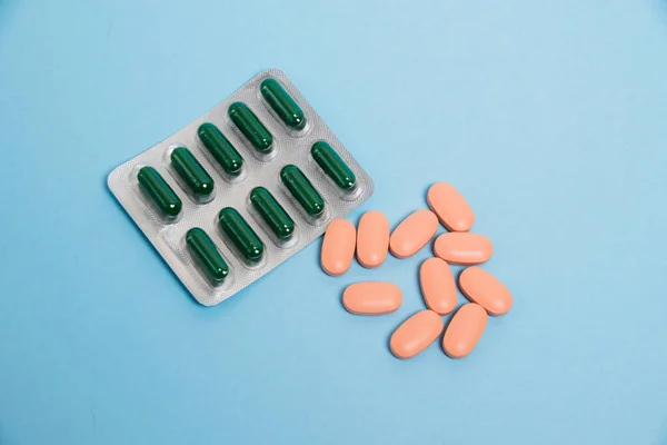 Vitamins in capsules and pills on a blue paper background. The concept of maintaining immunity and treating covid 19.