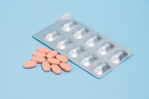 Pills in blisters and without on blue paper background with copy space