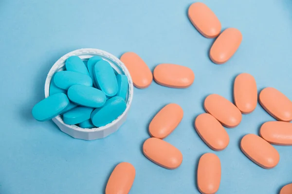 Blue and pink vitamins in pills for men and women on a blue paper background. The concept of differences in the needs of the female and male gender.
