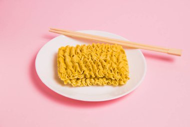 Beyaz tabakta hazır şehriye ve pembe arka planda çubuklar..