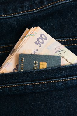 Ukrayna parası ve cebinde siyah kot pantolon olan bir kredi kartı.