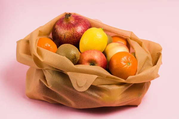 Reusable bag with fruit on a pink background. Earth day and zero waste concept