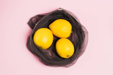 Pembe arka planda meyve ve sebzeler için yeniden kullanılabilir ağdaki limonlar. Toprak günü kavramı, sıfır atık ve geri dönüşüm