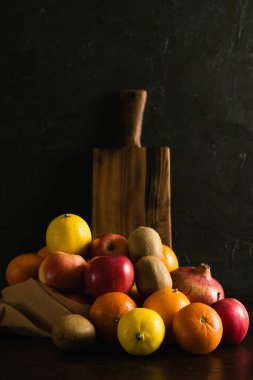 Tekrar kullanılabilir bir çantada meyve. Dünya günü ve sıfır atık kavramı. Portakal, limon, elma, kivi, nar ve ahşap kesim tahtası..