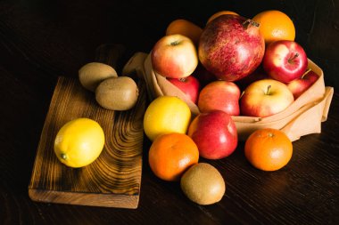 Tekrar kullanılabilir bir çantada meyve. Dünya günü ve sıfır atık kavramı. Portakal, limon, elma, kivi, nar ve ahşap kesim tahtası..