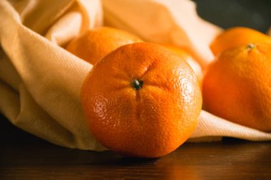 Toprak günü kavramı, geri dönüşüm ve sıfır atık. Koyu arkaplanda meyve ve sebzeler için tekrar kullanılabilir kahverengi bir çantada tatlı mandalinalar..