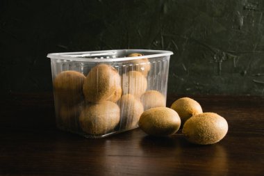 Toprak günü kavramı, geri dönüşüm ve sıfır atık. Siyah arka planda plastik bir sepetteki tatlı kivi.