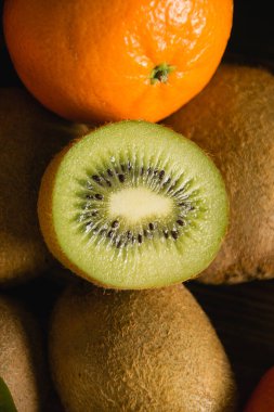 Flatlay, portakal, yarım kivi makrosu ve koyu arkaplanda bütün kivi..