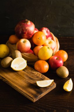 Tekrar kullanılabilir bir çantada meyve. Dünya günü ve sıfır atık kavramı. Kesme tahtasında dilimlenmiş limon, nar, portakal, mandalina, elma ve kivi..