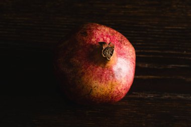 Koyu ahşap arka plan makrosunda kırmızı bir nar..