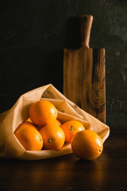 Toprak günü kavramı, gübreleme, sıfır atık ve geri dönüşüm. Sebzeler için yeniden kullanılabilir bir çantada portakallar ve arka planda meyveler ve ahşap kesim tahtası.