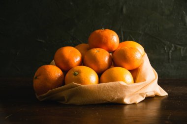 Toprak günü kavramı, gübreleme, sıfır atık ve geri dönüşüm. Arka planda sebze ve meyveler için yeniden kullanılabilir bir çantada portakallar.