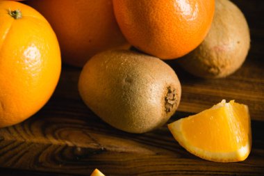 Koyu arkaplanda meyveler. Tahta kesme tahtasına portakal ve kivi yakın çekim.