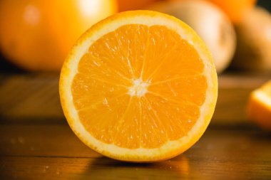 Koyu arkaplanda meyveler. Yarısı portakal, yarısı portakal ve kivi..