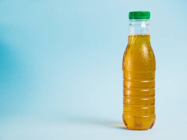 Mavi arka planda plastik bir şişede elma suyu. Dünya ve sıfır atık kavramı.