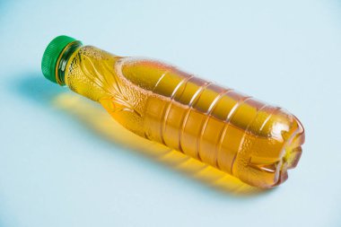 Mavi arka planda plastik bir şişede elma suyu. Toprak günü kavramı, sıfır atık ve plastik geri dönüşümü