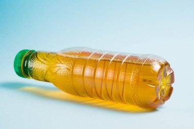 Mavi arka planda plastik bir şişede elma suyu. Toprak günü kavramı, sıfır atık ve plastik geri dönüşümü