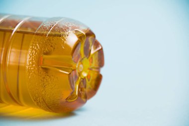 Mavi arka planda plastik bir şişede elma suyu. Toprak günü kavramı, sıfır atık ve plastik geri dönüşümü