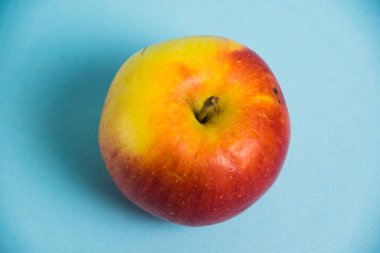 Mavi arka planda sulu kırmızı sarı elma. Toprak günü kavramı, sıfır atık ve plastik geri dönüşümü