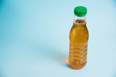 Mavi arka planda plastik bir şişede meyve suyu. Toprak günü kavramı, sıfır atık ve plastik geri dönüşümü