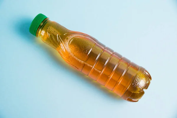 Apple juice in a plastic bottle on a blue background. Concept of earth day, zero waste and plastic recycling