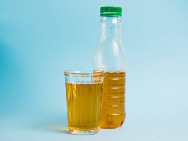 Mavi kağıdın üzerinde bir bardak meyve suyu ve plastik şişe. Toprak günü kavramı, sıfır atık ve plastik geri dönüşümü