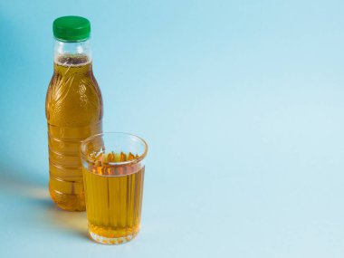 Mavi kağıdın üzerinde bir bardak meyve suyu ve plastik şişe. Toprak günü kavramı, sıfır atık ve plastik geri dönüşümü