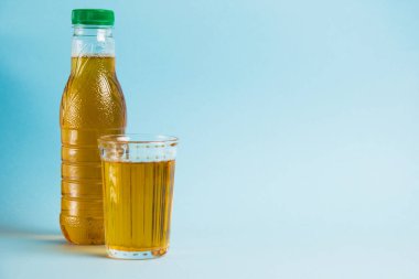 Mavi kağıdın üzerinde bir bardak meyve suyu ve plastik şişe. Toprak günü kavramı, sıfır atık ve plastik geri dönüşümü