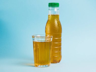 Mavi kağıdın üzerinde bir bardak meyve suyu ve plastik şişe. Toprak günü kavramı, sıfır atık ve plastik geri dönüşümü