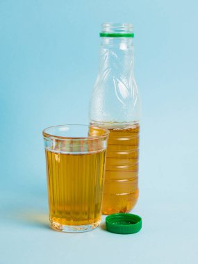 Plastik şişede meyve suyu ve arka planda yeniden kullanılabilir cam bardak iç. Toprak günü kavramı, sıfır atık ve plastik geri dönüşümü