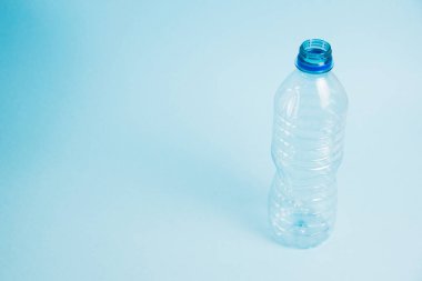 Mavi arka planda şeffaf plastik şişe. Toprak günü kavramı, sıfır atık ve plastik geri dönüşümü