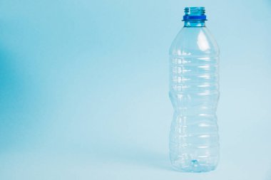Mavi arka planda şeffaf plastik şişe. Toprak günü kavramı, sıfır atık ve plastik geri dönüşümü